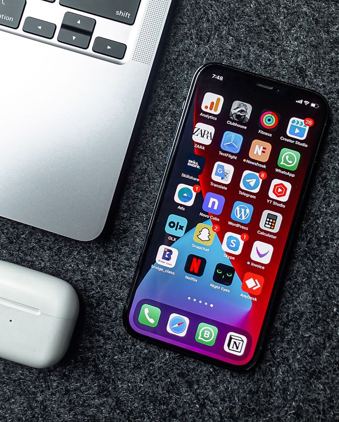 A flat lay featuring a smartphone, laptop, and earphones arranged on a grey surface. Ideal for technology and gadget-focused themes.